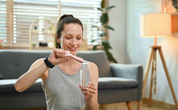 woman pouring collagen powder into water