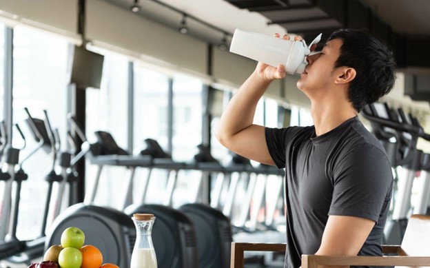 man drinking protein shake in gym