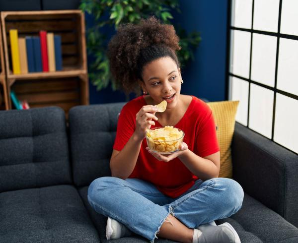 woman eating chips on couch